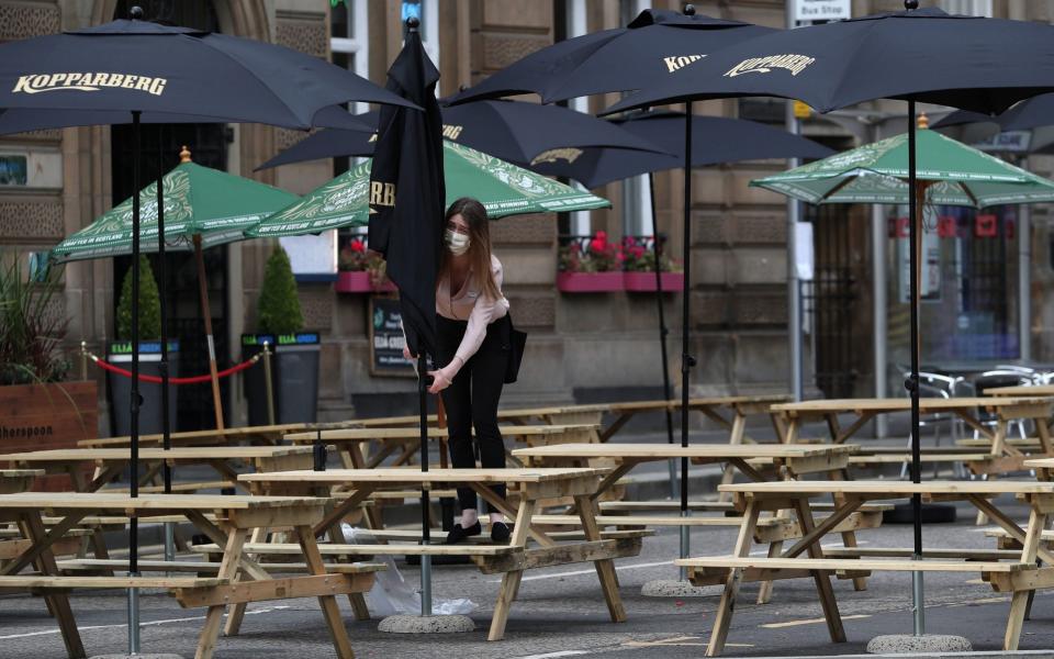 A waitress adjusts a canopy at a restaurant seating area in Glasgow as First Minister Nicola Sturgeon announced the latest coronavirus restrictions to the Scottish Parliament - PA