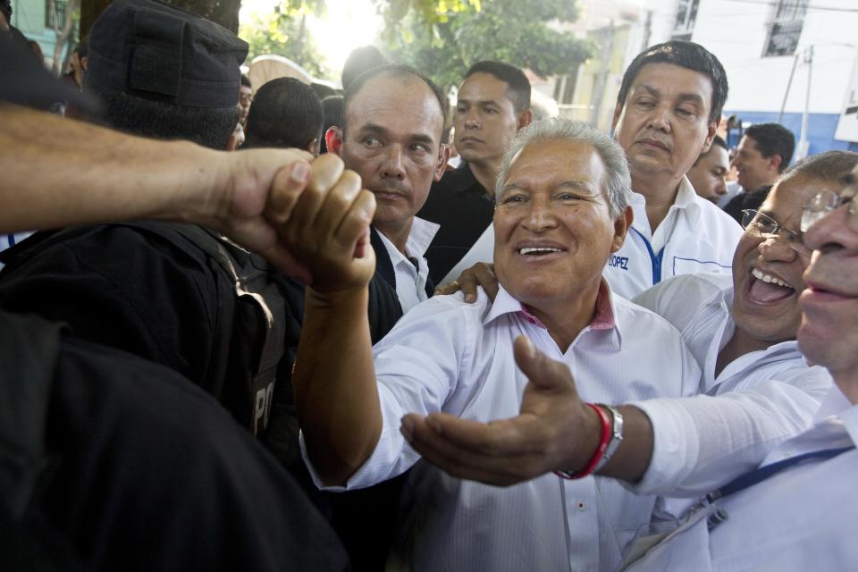 Presidential candidate Salvador Sanchez Ceren, the current vice president for the ruling Farabundo Marti National Liberation Front (FMLN), center, and his running mate Oscar Ortiz, right, greet supporters after casting their votes in the presidential runoff election in San Salvador, El Salvador, Sunday, March 9, 2014. Sanchez Ceren is running against former San Salvador Mayor Norman Quijano from the Nationalist Republican Alliance (ARENA). (AP Photo/Esteban Felix)