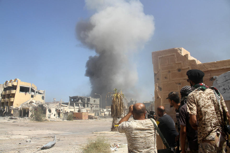 Smoke rises as Libyan forces take cover during a battle with Islamic State militants in Sirte