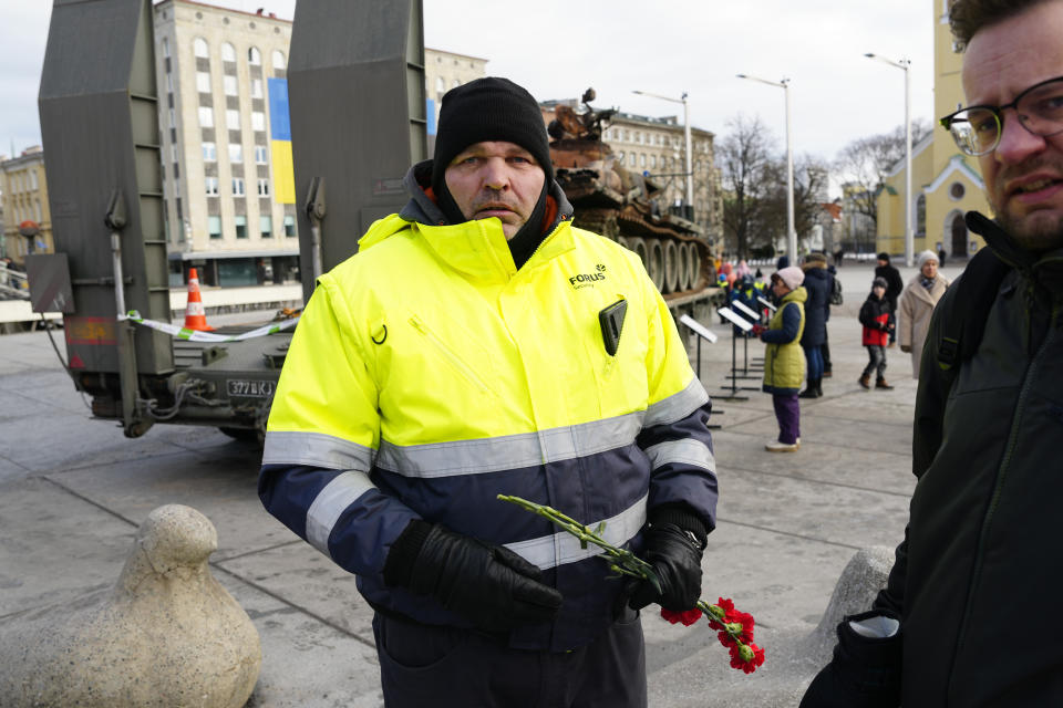 A security guard removes flowers placed on a destroyed Russian T-72B3 tank installed as a symbol of the Russia Ukraine war to mark the first anniversary of Russia's full-scale invasion of Ukraine, in Freedom Square in Tallinn, Estonia, Wednesday, March 1, 2023. (AP Photo/Pavel Golovkin)