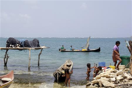 Children play at the beach as a local boat passes by the coast of Caledonia island in the region of Guna Yala April 4, 2014. REUTERS/ Carlos Jasso