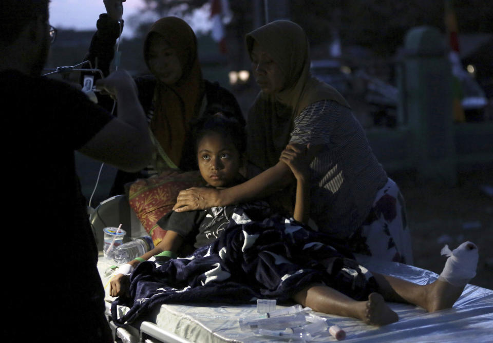 In this Tuesday, Aug. 7, 2018, photo, a doctor examines a child injured in the earthquake at a makeshift hospital in Tanjung, North Lombok, Indonesia. (AP Photo/Tatan Syuflana)