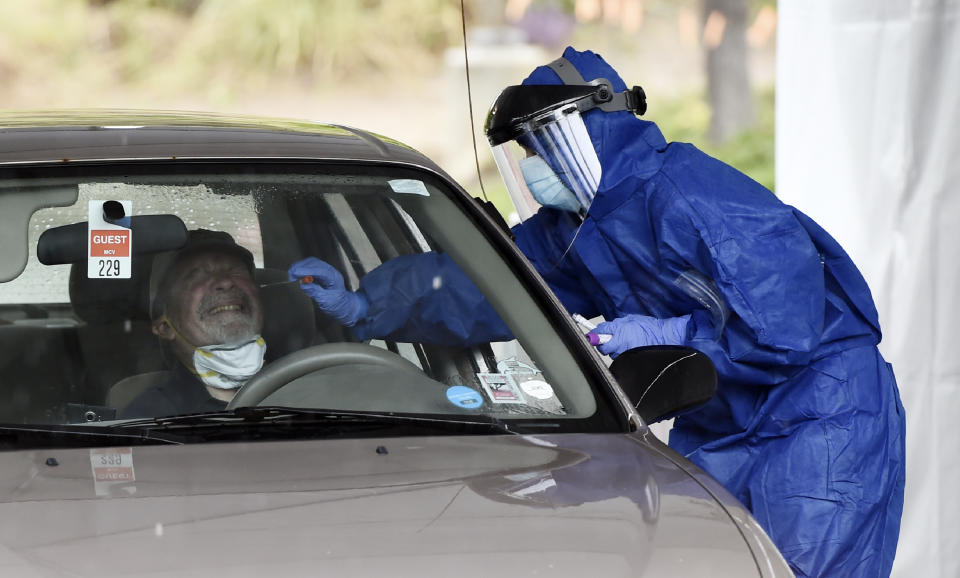 En esta foto del 9 de abril del 2020, un trabajador de la salud realiza una prueba de coronavirus en un centro de atención gratuita desde el auto de la organización del actor Sean Penn, CORE, en el ayuntamiento de Malibú, California. El actor ganador del Oscar se asoció con la oficina del alcalde de Los Ángeles Eric Garcetti y el departamento de bomberos de la ciudad para realizar de manera segura pruebas de COVID-19 a personas con síntomas del virus. (AP Foto/Chris Pizzello)