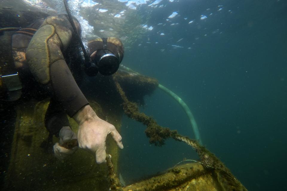 A diver pulls a shipwreck's rope during a raising operation, on Salamina island, west of Athens, on Wednesday, Feb. 13, 2020. Greece this year is commemorating one of the greatest naval battles in ancient history at Salamis, where the invading Persian navy suffered a heavy defeat 2,500 years ago. But before the celebrations can start in earnest, authorities and private donors are leaning into a massive decluttering operation. They are clearing the coastline of dozens of sunken and partially sunken cargo ships, sailboats and other abandoned vessels. (AP Photo/Thanassis Stavrakis)