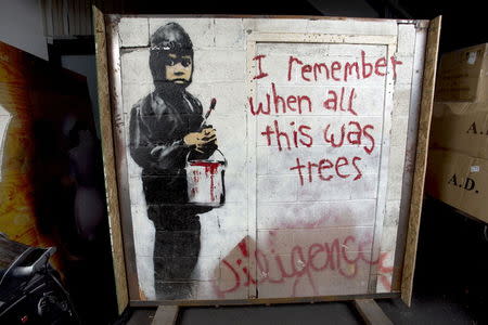 A painting entitled "I Remember When All This Was Trees" is shown inside its crate in a warehouse in Beverly Hills, California in this June 25, 2015 handout photo released to Reuters July 28, 2015. The huge street mural painted on a derelict Detroit auto factory by elusive British artist Banksy is going up for auction in Beverly Hills and could fetch up to $400,000 dollars for a local non-profit group, Julien's Auctions said on Wednesday. REUTERS/Julien's Auctions/Handout via Reuters