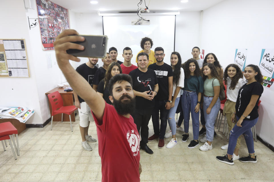 In this Thursday, Aug. 29, 2019 photo, an activist takes a photo of Ayman Odeh, venter, the leader of the Arab Joint List parties, wiht party activists during a campaign meeting in Nazareth, Israel. Odeh has shaken up Israel's election campaign by offering to sit in a moderate coalition government _ a development that would upend decades of convention that has relegated Arab parties to the sidelines and could bring down Prime Minister Benjamin Netanyahu. (AP Photo/Mahmoud Illean)