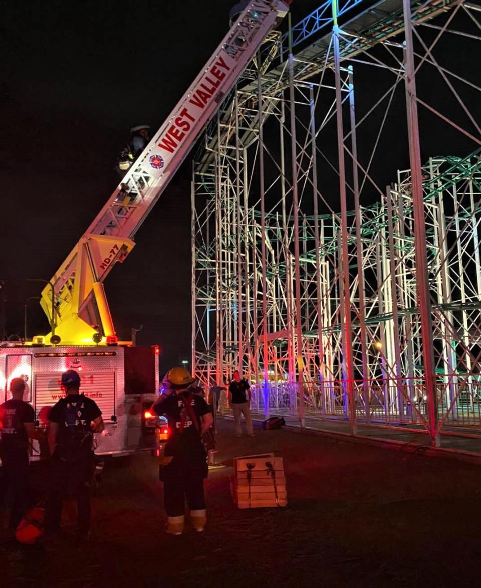 West Valley firefighters climb a ladder truck to reach riders stuck on a roller coaster at Western Playland Amusement Park in Sunland Park, New Mexico, on Saturday, July 24, 2021.