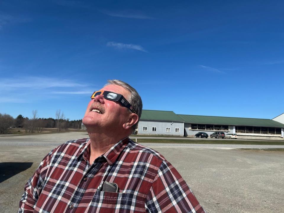 Bill Rowell, owner of Green Mountain Dairy in Sheldon, Vermont, checks on the progress of the moon covering the sun, as seen on April 8, 2024.