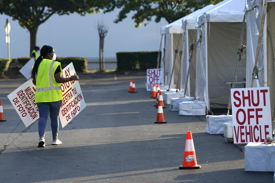 A healthcare worker puts out signs at a Texas Division of Emergency Management free COVID-19 testing site at Minute Maid Park Saturday, Aug. 8, 2020, in Houston. The newly opened mega site, which has eight drive-thru lanes and four walk-up lanes, has the ability to process 2,000 tests per day. (AP Photo/David J. Phillip)