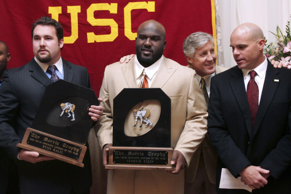 FILE - Southern California coach Pete Carroll chats with defensive coordinator Nick Holt, right, during a photo session with Morris Trophy winners, center Ryan Kalil, left, and nose tackle Sedrick Ellis, both of USC, at the Washington Athletic Club in Seattle, Jan. 18, 2007. The Morris Trophy was never a name-brand award handed out following the college football season, in part because it honored offensive and defensive linemen, players who sometimes don't get the recognition they deserve. But it was special on the West Coast and special to the Pac-10 or Pac-12. Every year since 1980 it's been awarded, and perhaps most notably was voted on by the players themselves. Coaches and media had no influence in the final decision. (AP Photo/Joe Nicholson, File)