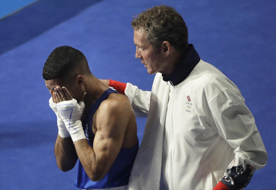 <p>Britain’s Galal Yafai is comforted by his coach after losing to Cuba’s Joahnys Argilagos in a men’s light flyweight 49-kg preliminary boxing match at the Summer Olympics in Rio de Janeiro, Brazil, Monday, Aug. 8, 2016. (AP Photo/Jae C. Hong) </p>