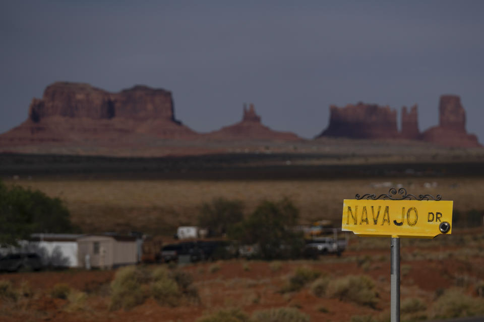 FILE - A sign marks Navajo Drive, as Sentinel Mesa, homes and other structures in Oljato-Monument Valley, Utah, on the Navajo Reservation, stand in the distance, on April 30, 2020. The U.S. Supreme Court will soon decide a critical water rights case in the water-scarce Southwest. The high court will hold oral arguments Monday, March 20, 2023, in a case with critical implications for how water from the drought-stricken Colorado River is shared and the extent of the U.S. government’s obligations to Native American tribes. (AP Photo/Carolyn Kaster, File)