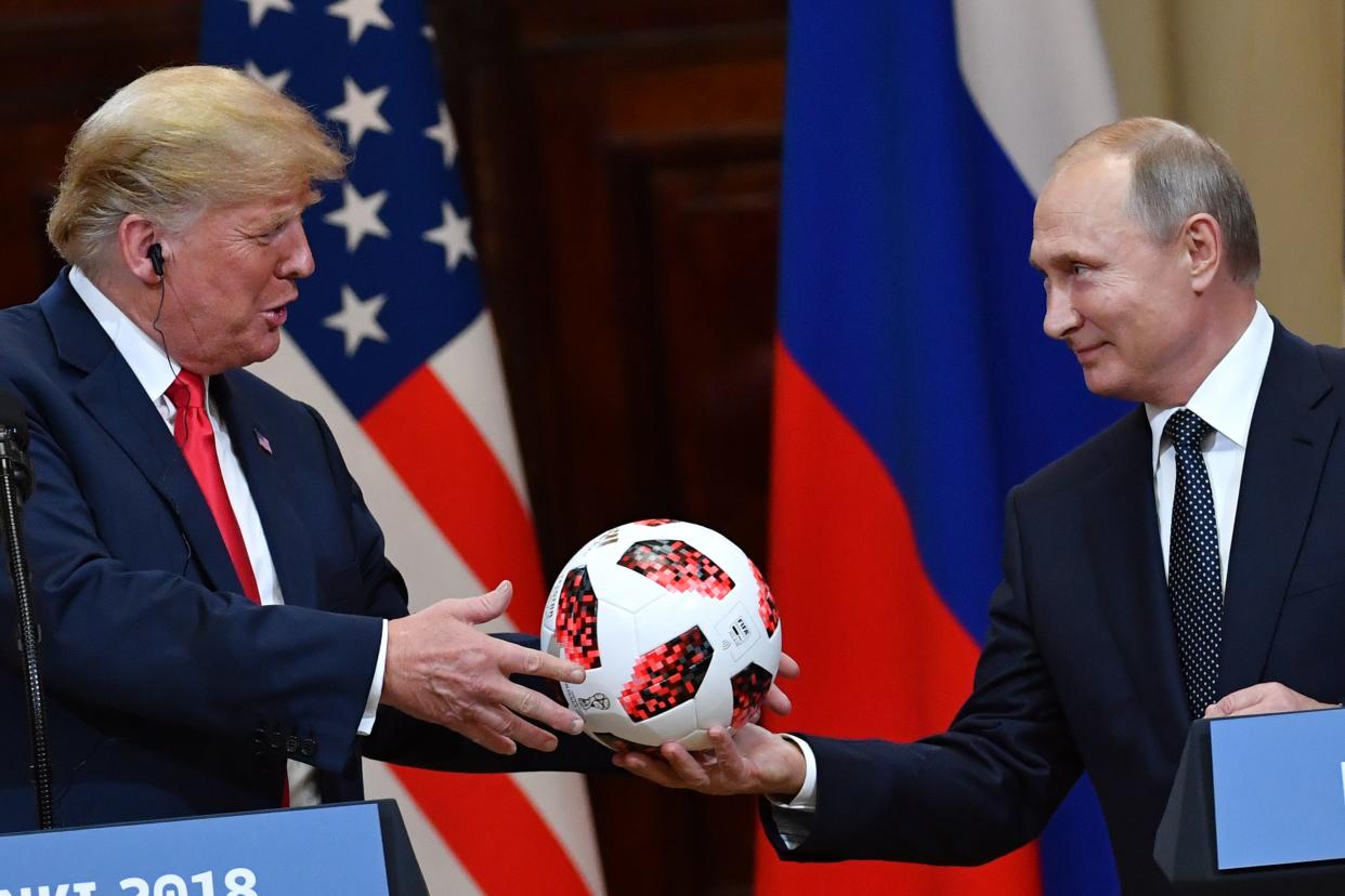 Russian President Vladimir Putin hands a 2018 World Cup soccer ball to then-President Donald Trump as they stand onstage in Helsinki.