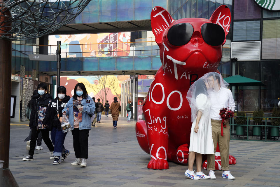 A couple poses for wedding photos in a popular shopping district in Beijing Thursday, Feb. 25, 2021. The state of the world's second largest economy takes precedence among the myriad issues presented by Chinese Premier Li Keqiang in his address at the National People's Congress opening session to take place on Friday, March 5. 2021. (AP Photo/Ng Han Guan)