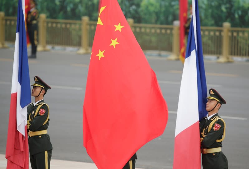 Members of honour guards holding Chinese and French flags attend a welcoming ceremony for French President Emmanuel Macron in Beijing