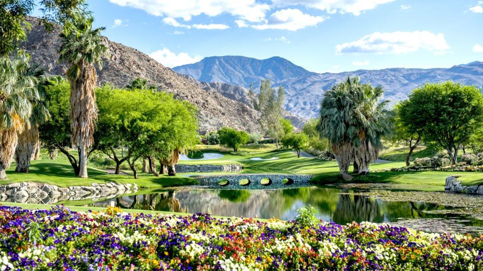 a luxury golf course with flowers and a bridge