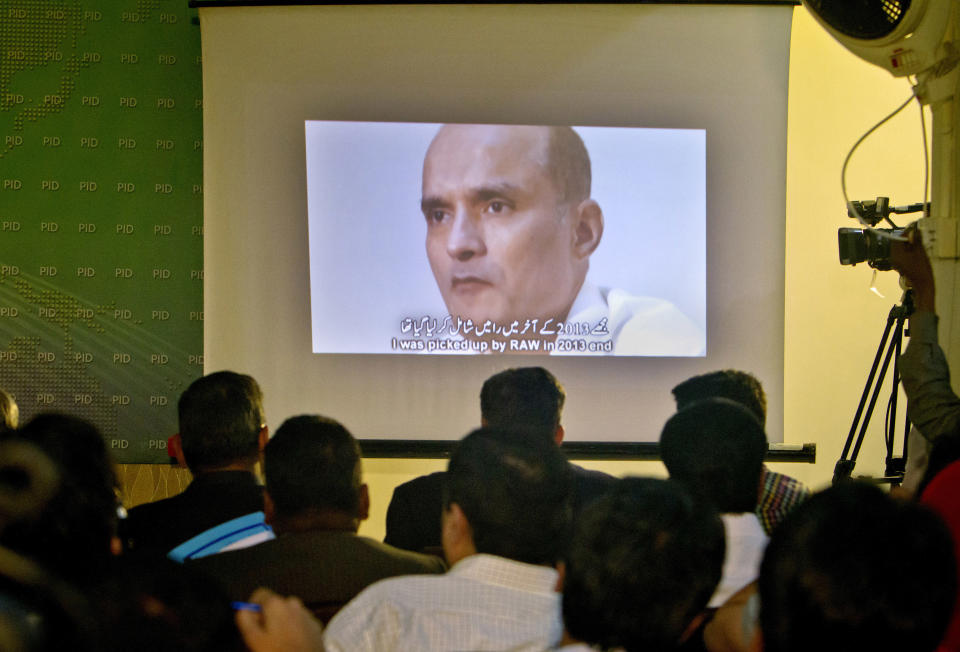 In this March 29, 2016 photo, journalists look a image of Indian naval officer Kulbhushan Jadhav, who was arrested in March 2016, during a press conference by Pakistan's army spokesman and the Information Minister, in Islamabad, Pakistan. The army said in a statement Monday, April 10, 2017, that Jadhav was sentenced to death on charges of espionage and sabotage. Pakistan says Jadhav was an Indian intelligence official who aided and financed terrorist activities. (AP Photo/Anjum Naveed)