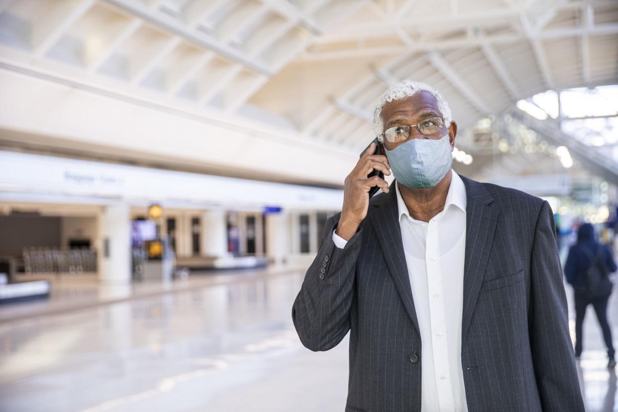 A Senior Black man using his phone in the airport