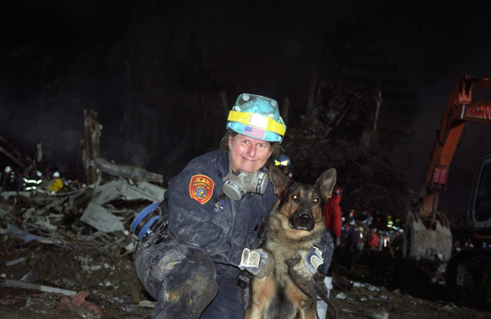 A firefighter holds a search and rescue dog which was used to hunt for survivors. (Caters)