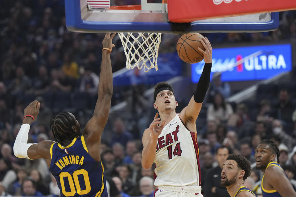 Miami Heat guard Tyler Herro (14) drives to the basket as Golden State Warriors forward Jonathan Kuminga (00) defends during the first half of an NBA basketball game Thursday, Dec. 28, 2023, in San Francisco. (AP Photo/Loren Elliott)