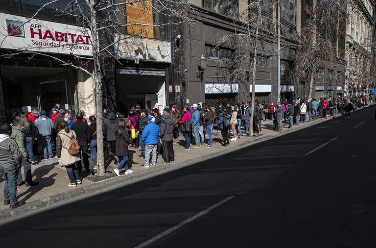 En esta foto del 17 de agosto de 2020, cientos de personas esperan frente a la oficina de administración de pensiones, AFP, para solicitar un retiro anticipado de un porcentaje de sus pensiones gubernamentales  en el centro de Santiago, Chile. (AP Foto/Esteban Felix, Archivo)