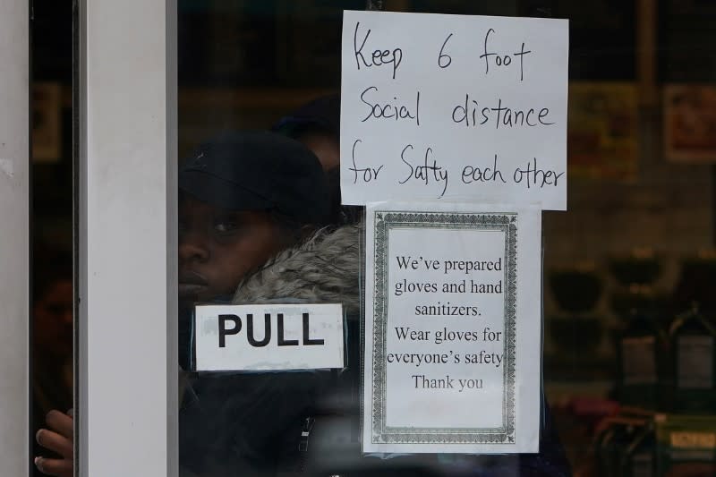 A woman walks out of a store that has a "Social Distancing" sign on the door during the outbreak of coronavirus disease (COVID-19), in the Manhattan borough of New York City