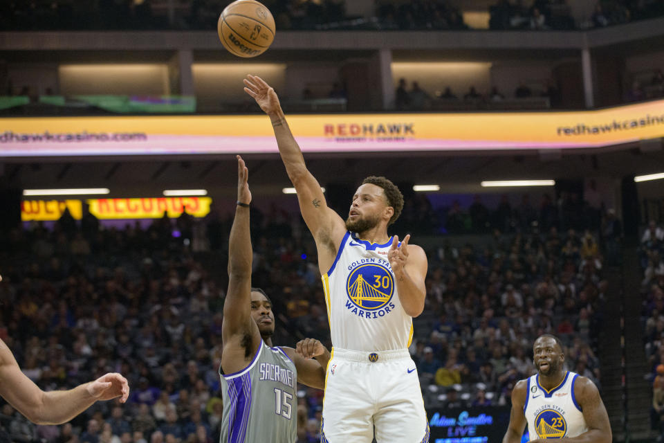 Golden State Warriors guard Stephen Curry (30) shoots over Sacramento Kings guard Davion Mitchell (15) during the first quarter of an NBA basketball game in Sacramento, Calif., Sunday, Nov. 13, 2022. (AP Photo/Randall Benton)