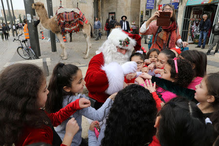 A group of girls stand around Israeli-Arab Issa Kassissieh, wearing a Santa Claus costume, during the annual Christmas tree distribution by the Jerusalem municipality in Jerusalem's Old City December 21, 2017. REUTERS/Ammar Awad