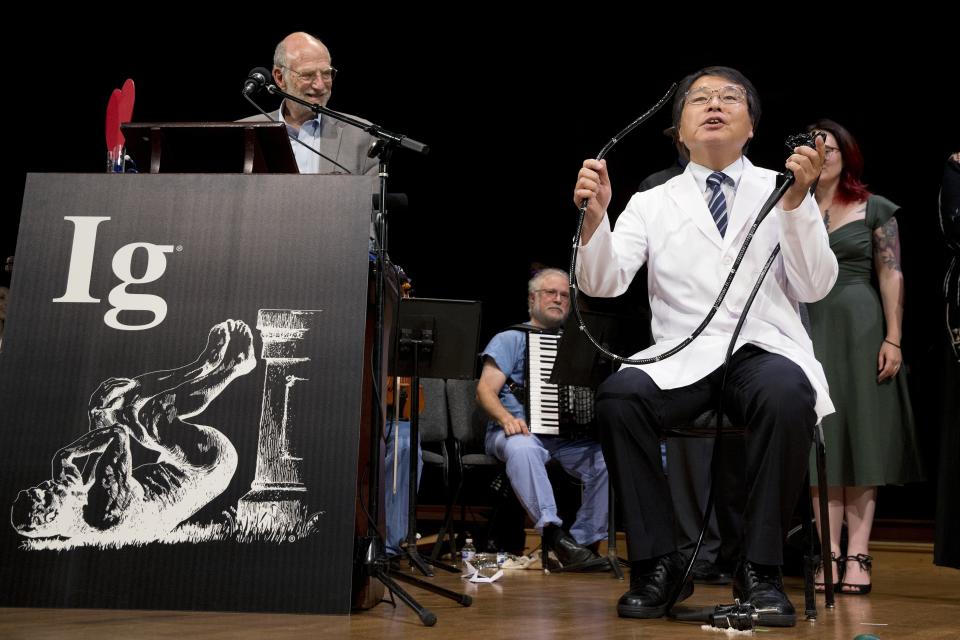 Akira Horiuchi, right, of Japan, who won the Ig Nobel in medical education demonstrates his self colonoscopy technic during award ceremonies at Harvard University in Cambridge, Mass., Thursday, Sept. 13, 2018.(AP Photo/Michael Dwyer)