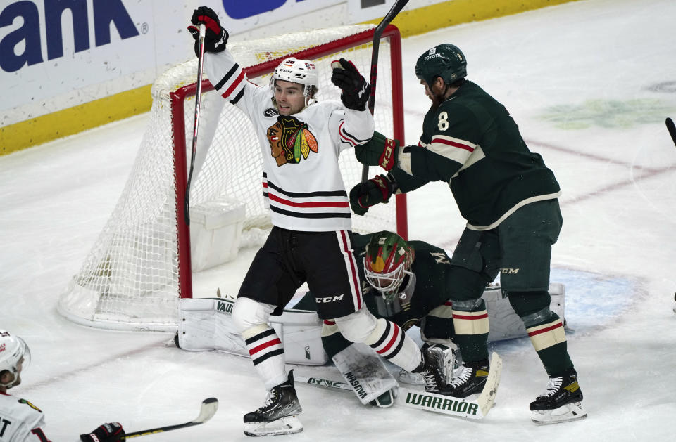 Chicago Blackhawks' Brandon Hagel, left, celebrates a power-play goal by Alex DeBrincat against Minnesota Wild goalie Kaapo Kahkonen, bottom, during the first period of an NHL hockey game Saturday, Jan. 22, 2022, in St. Paul, Minn. (AP Photo/Jim Mone)