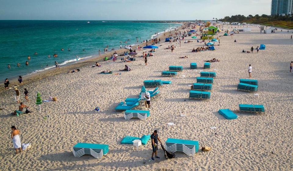 Los vigilantes de la playa recogiendo las tumbonas y sombrillas mientras la playa cierra al público a las 6:00 p.m. en South Beach durante las vacaciones de primavera en Miami Beach el sábado 16 de marzo de 2024.