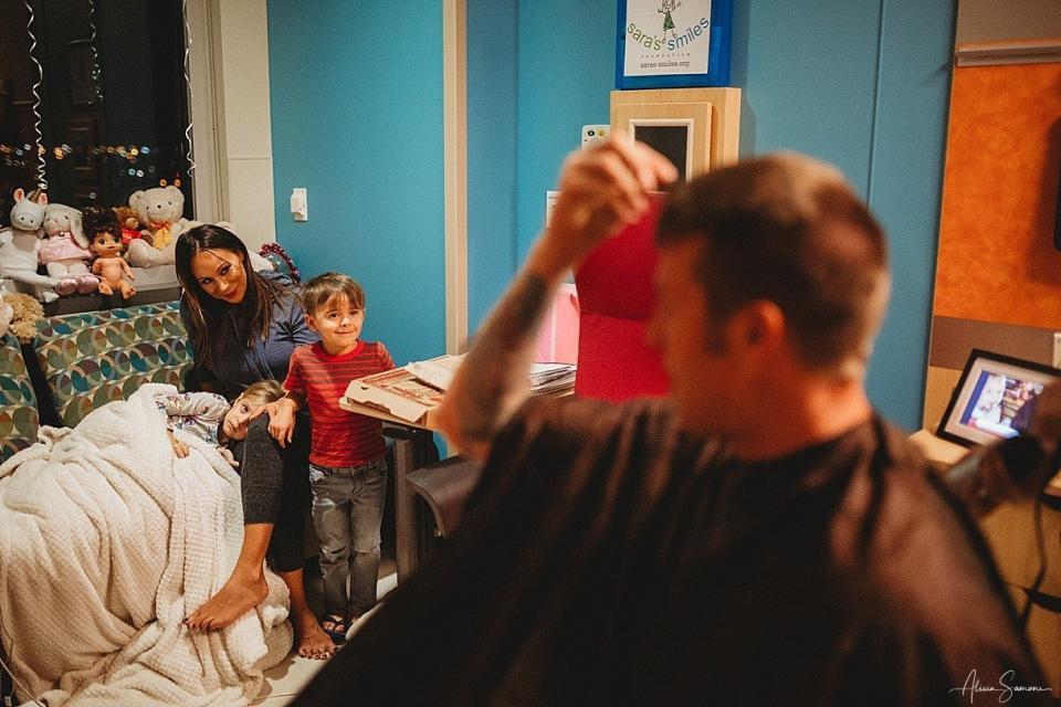 Madi, alongside her mother and brother, watches as her father prepares to cut his hair in solidarity. (Photo: Alicia Samone Photography)