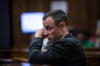 Oscar Pistorius, wipes his eye during crime scene photographs as he sits in the dock in court in Pretoria, South Africa, Monday, March 17, 2014. Pistorius is on trial for the murder of his girlfriend Reeva Steenkamp on Valentines Day, 2013. (AP Photo/Daniel Born, Pool)