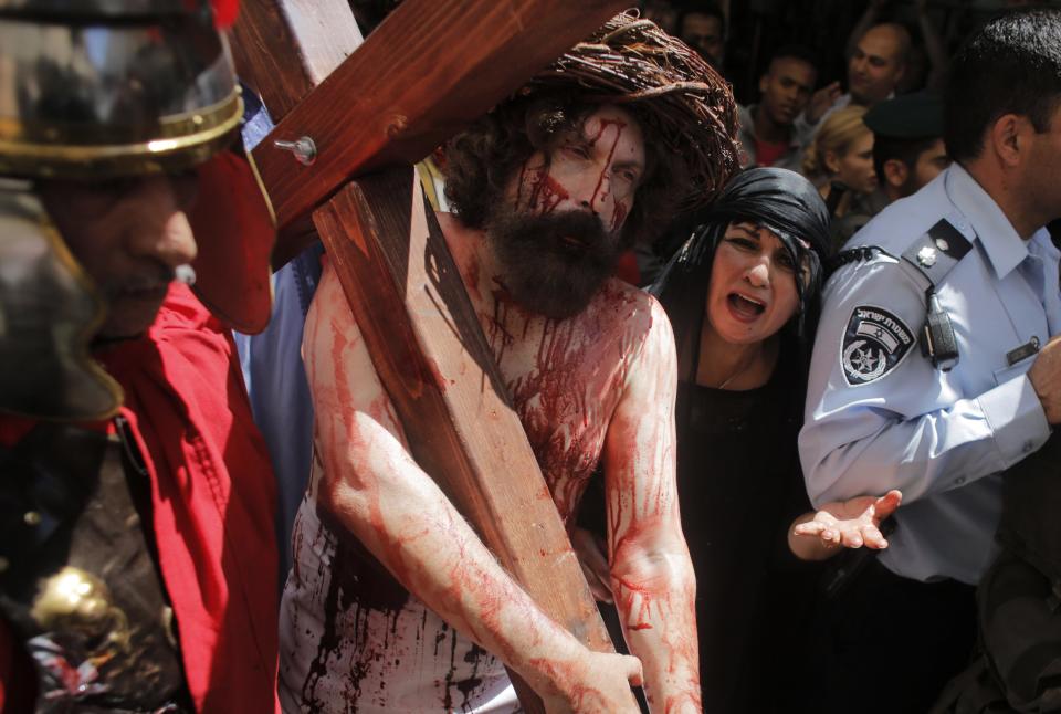 A man playing the role of Jesus carries a cross during a procession along the Via Dolorosa on Good Friday in Jerusalem's Old City