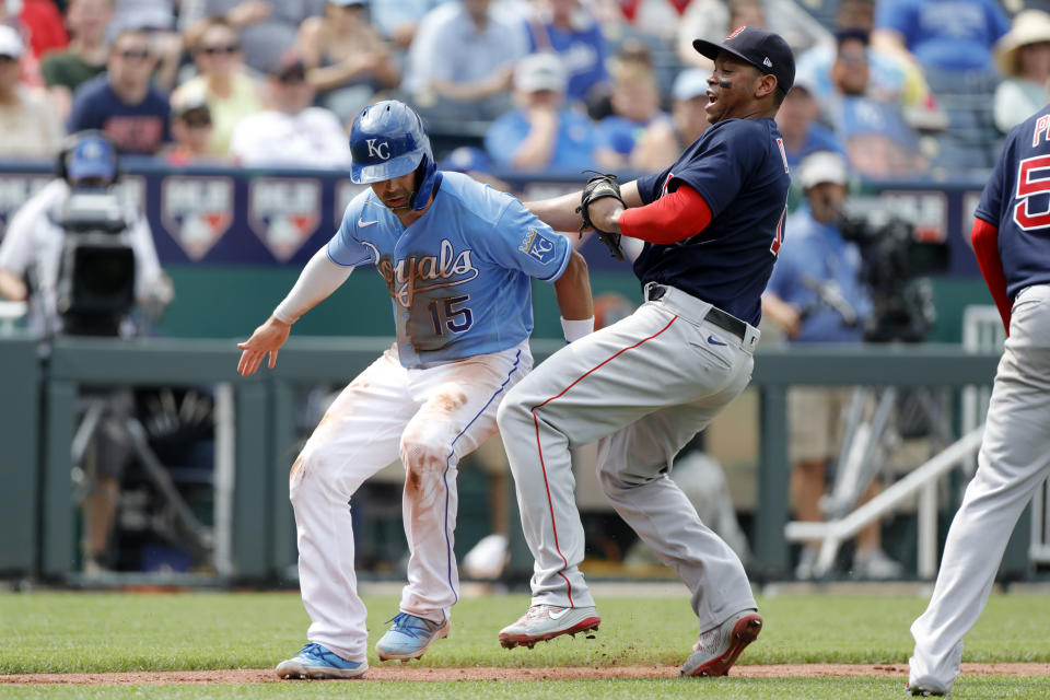 Kansas City Royals' Whit Merrifield, left, is tagged out by Boston Red Sox third baseman Rafael Devers, right, during a rundown between home plate and third base in the third inning of a baseball game at Kauffman Stadium in Kansas City, Mo., Saturday, June 19, 2021. (AP Photo/Colin E. Braley)