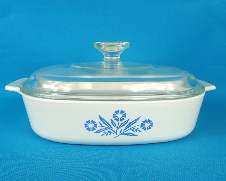 A white casserole dish with blue daisies drawn on it