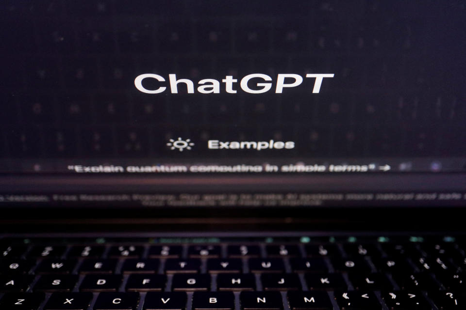 A keyboard is seen reflected on a computer screen displaying the website of ChatGPT.