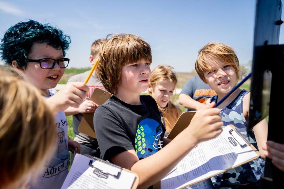 Wyatt Billings, a 4th grade teacher at the Barry, Ill.-based Western Elementary School, looks over an educational placard alongside Briggs Renecker, right, and other classmates on Wednesday, April 12, 2023, at the New Philadelphia National Historic Site in New Philadelphia, Ill. Brian Munoz/Brian Munoz