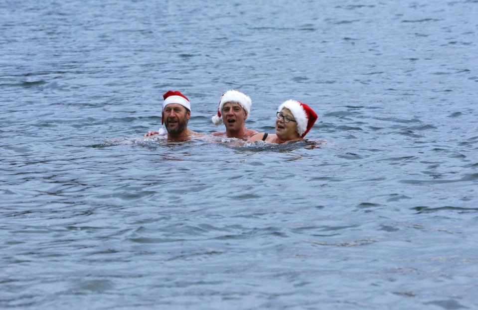 Members of the ice swimming club "Berliner Seehunde" (Berlin Seals) sing as they take a dip in the Orankesee lake in Berlin as part of their traditional Christmas ice swimming session