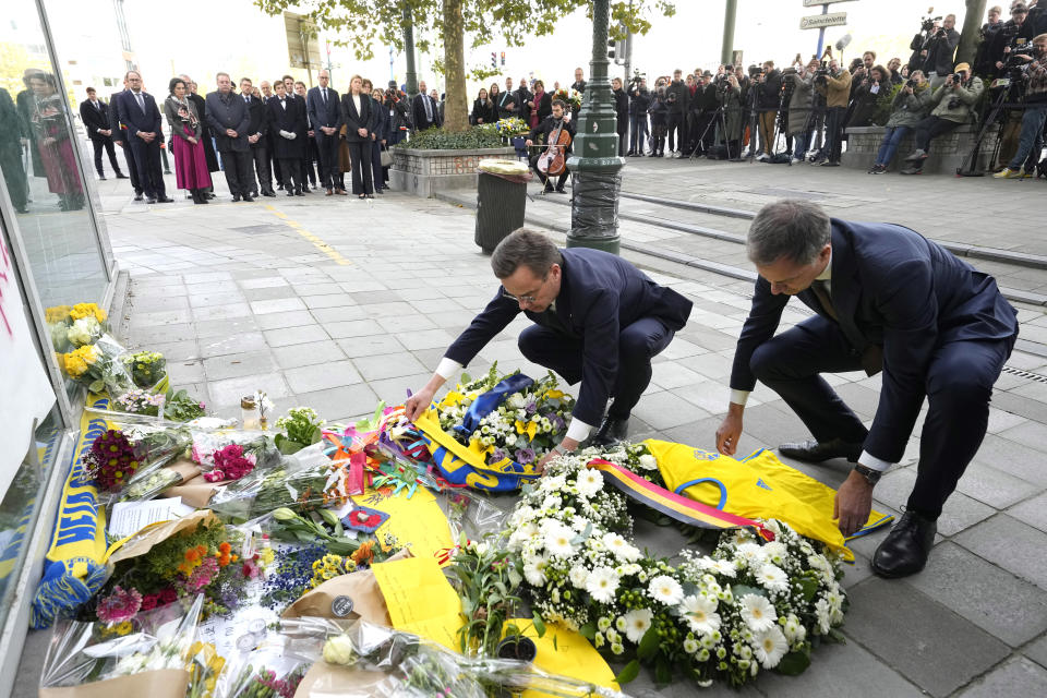 El primer ministro sueco Ulf Kristersson (izquierda) y su homólogo belga Alexander De Croo (derecha), colocan el miércoles 18 de octubre de 2023 una corona de flores y una camiseta de la selección de fútbol de Suecia en el pavimento durante un acto de homenaje a las víctimas de un tiroteo en Bruselas. (AP Foto/Martin Meissner)