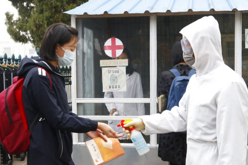 2021年11月，北韓的中學女生在進入學校前由防疫人員用酒精消毒雙手。（美聯社）