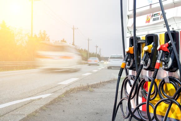 A fuel pump by the side of a road with a blur of cars