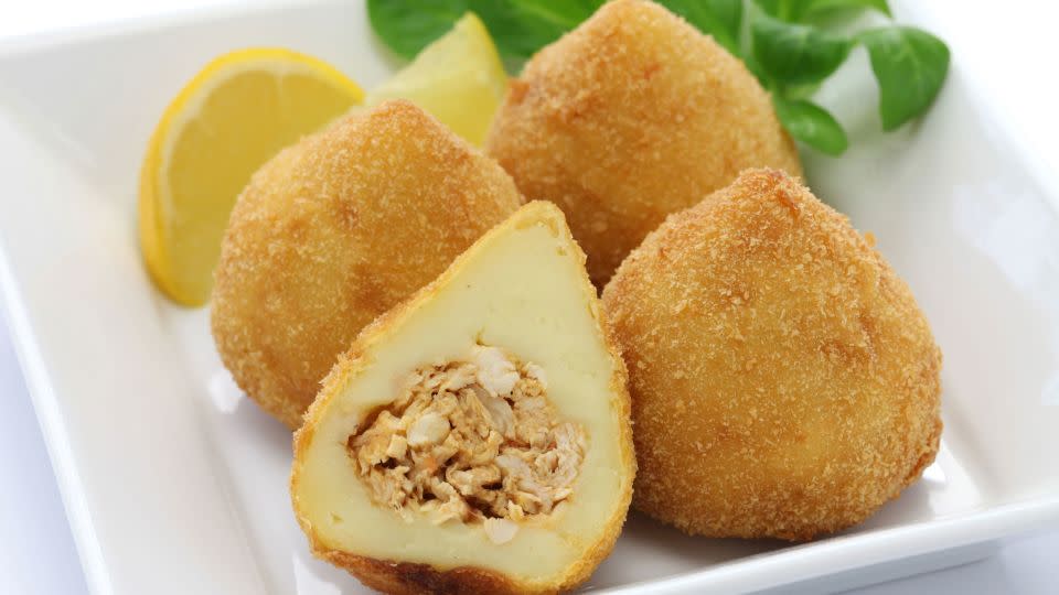 Coxinha are fried dough balls with shredded chicken inside. - Adobe Stock