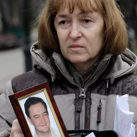 Nataliya Magnitskaya, the mother of Sergei Magnitsky, holds a photo of her son following his death in a Russian jail in 2009 - Credit: Alexander Zemlianichenko/AP