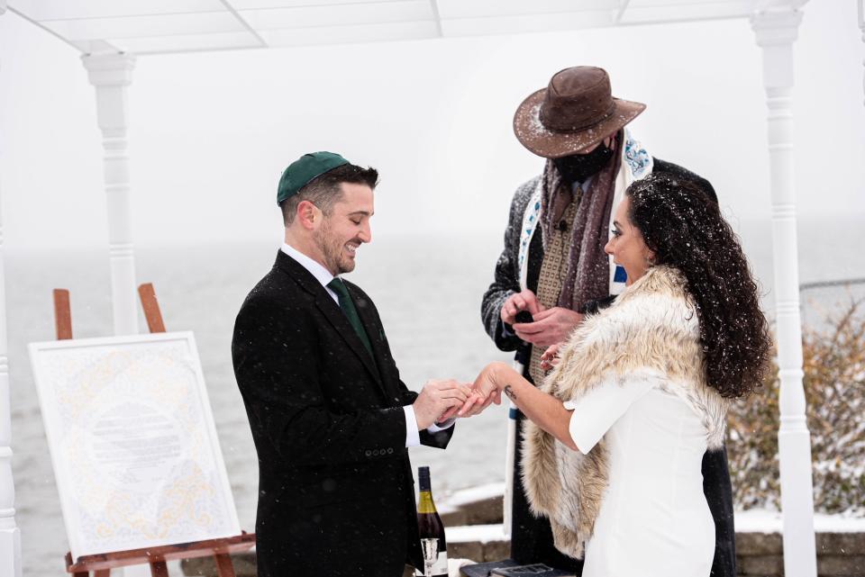 The couple stands with the officiant at their backyard wedding in the winter