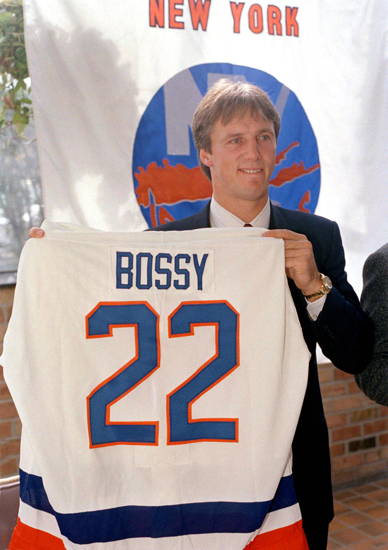 FILE - Mike Bossy holds his New York Islanders uniform up at a news conference in New York, Oct. 24, 1988. Bossy, one of hockey’s most prolific goal-scorers and a star for the New York Islanders during their 1980s dynasty, died Friday, April 15, 2022, after a battle with lung cancer. He was 65. (AP Photo/Gerald Herbert, File)