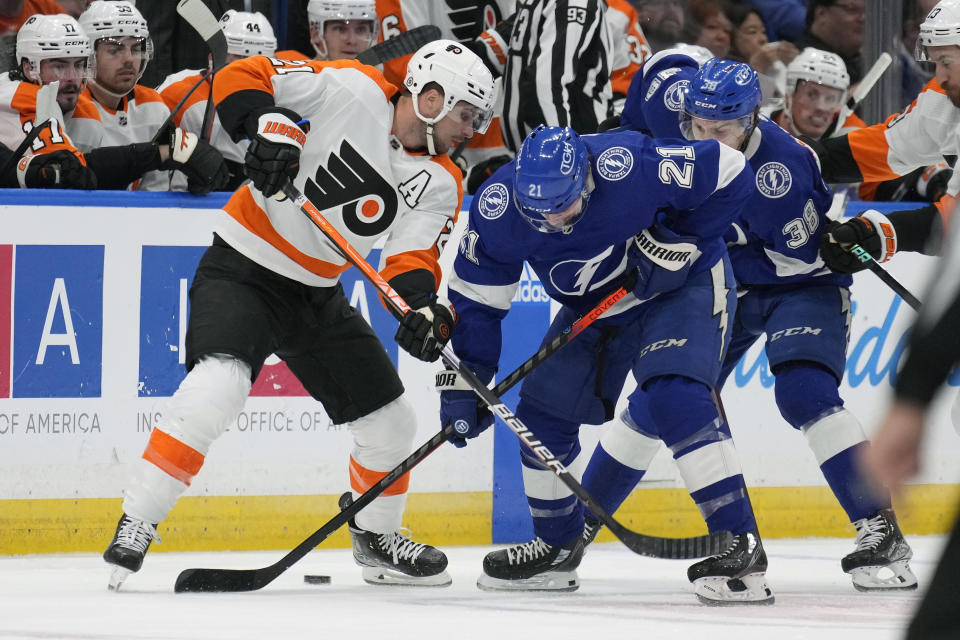 Philadelphia Flyers center Scott Laughton, left, battles for the puck with Tampa Bay Lightning center Brayden Point, center, and left wing Brandon Hagel, right, during the first period of an NHL hockey game Tuesday, Oct. 18, 2022, in Tampa, Fla. (AP Photo/Chris O'Meara)