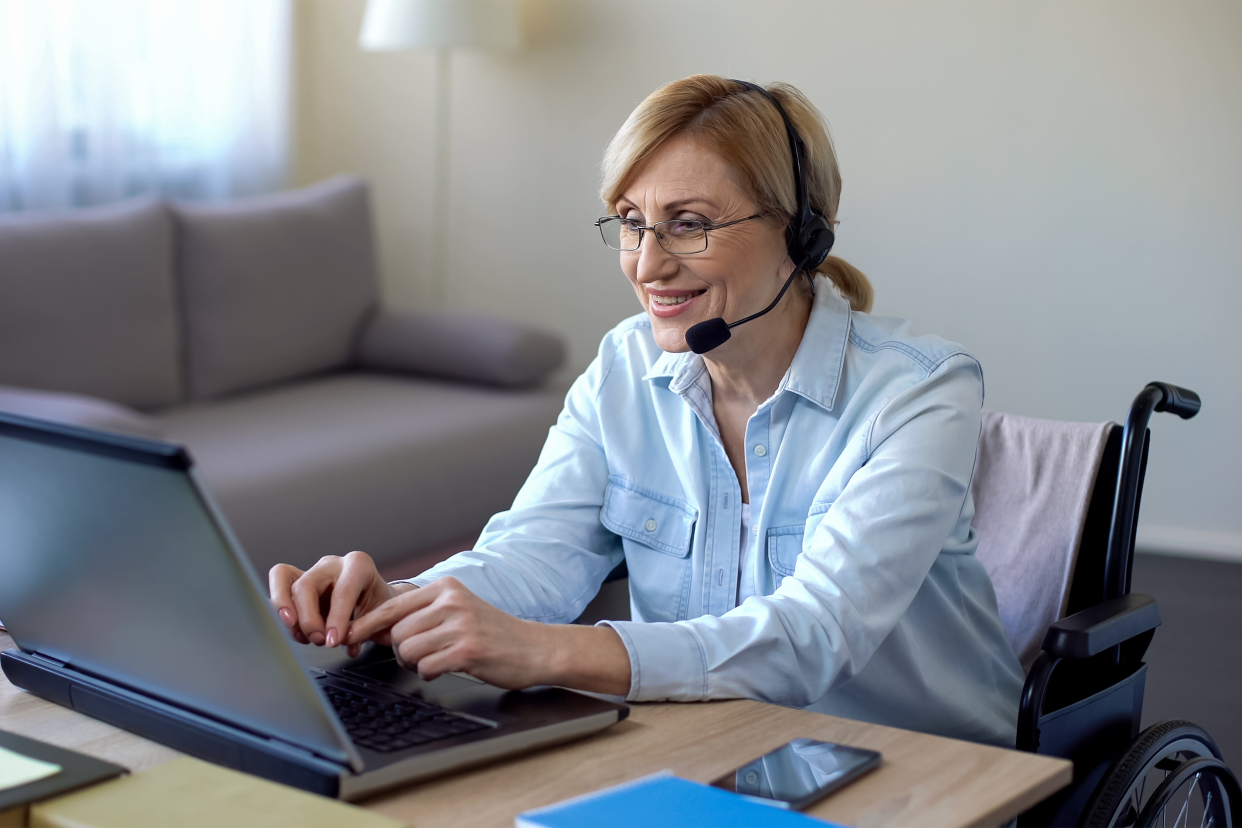 Senior woman working on her laptop with a headset