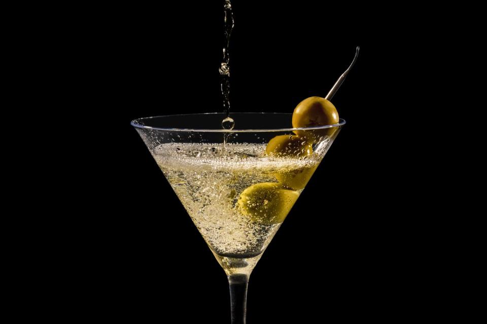 close up of pouring and splashing martini glass with olives