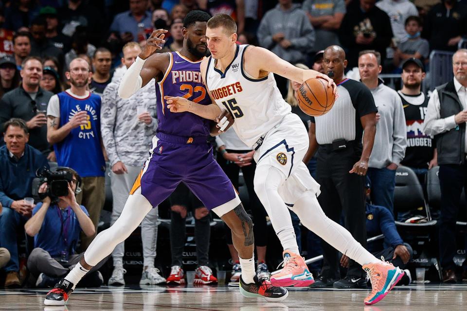 Mar 24, 2022; Denver, Colorado, USA; Denver Nuggets center Nikola Jokic (15) controls the ball as Phoenix Suns center Deandre Ayton (22) guards in the first quarter at Ball Arena.